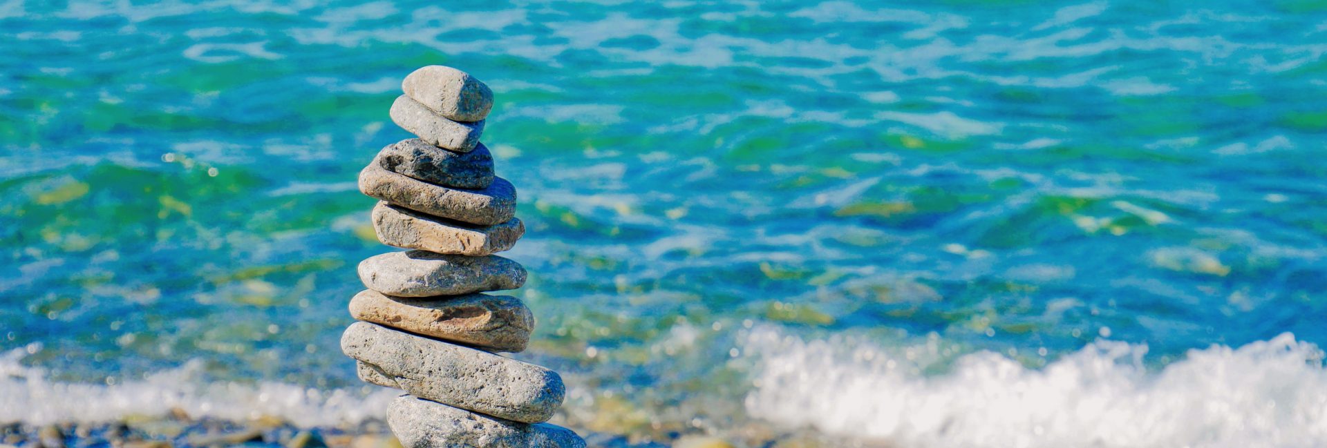 Stones balanced in a tower next to a beautiful blue sea