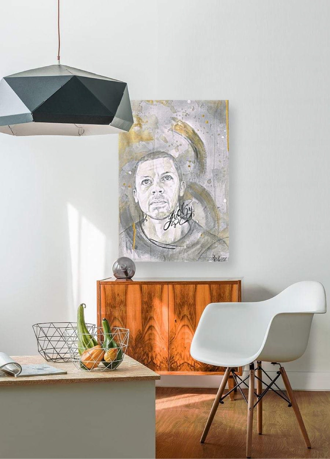 Photo of a room with a brown side table against a white wall. Above the side table is a drawing of the singer Will Young.